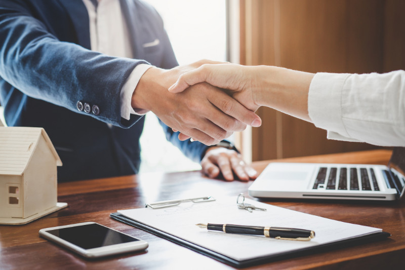 Real estate agent and customers shaking hands together